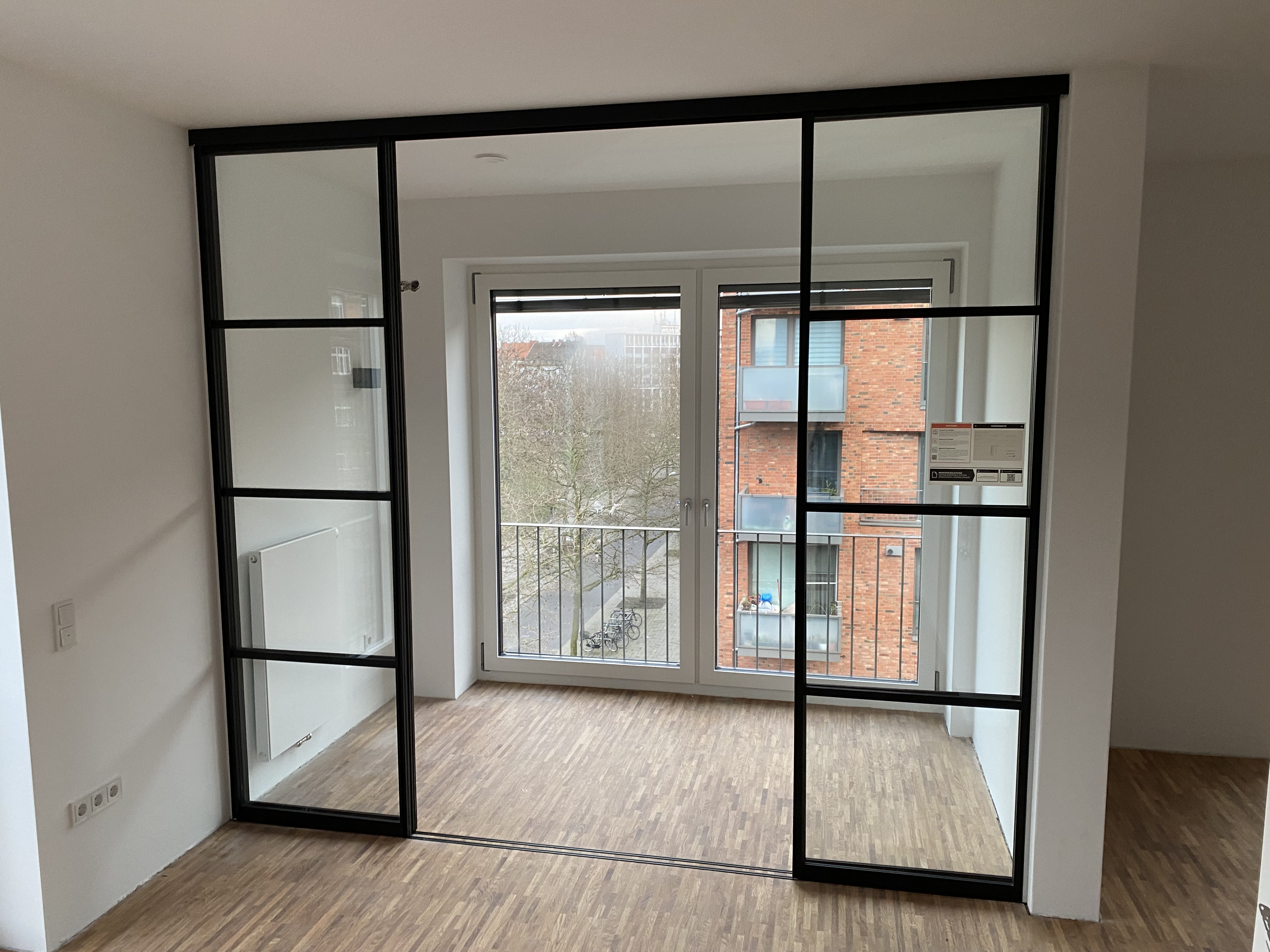 Loft-Schiebetür aus Glas und Aluminium mit schwarzer Sprossenoptik für lichtdurchflutete und moderne Raumkonzepte.