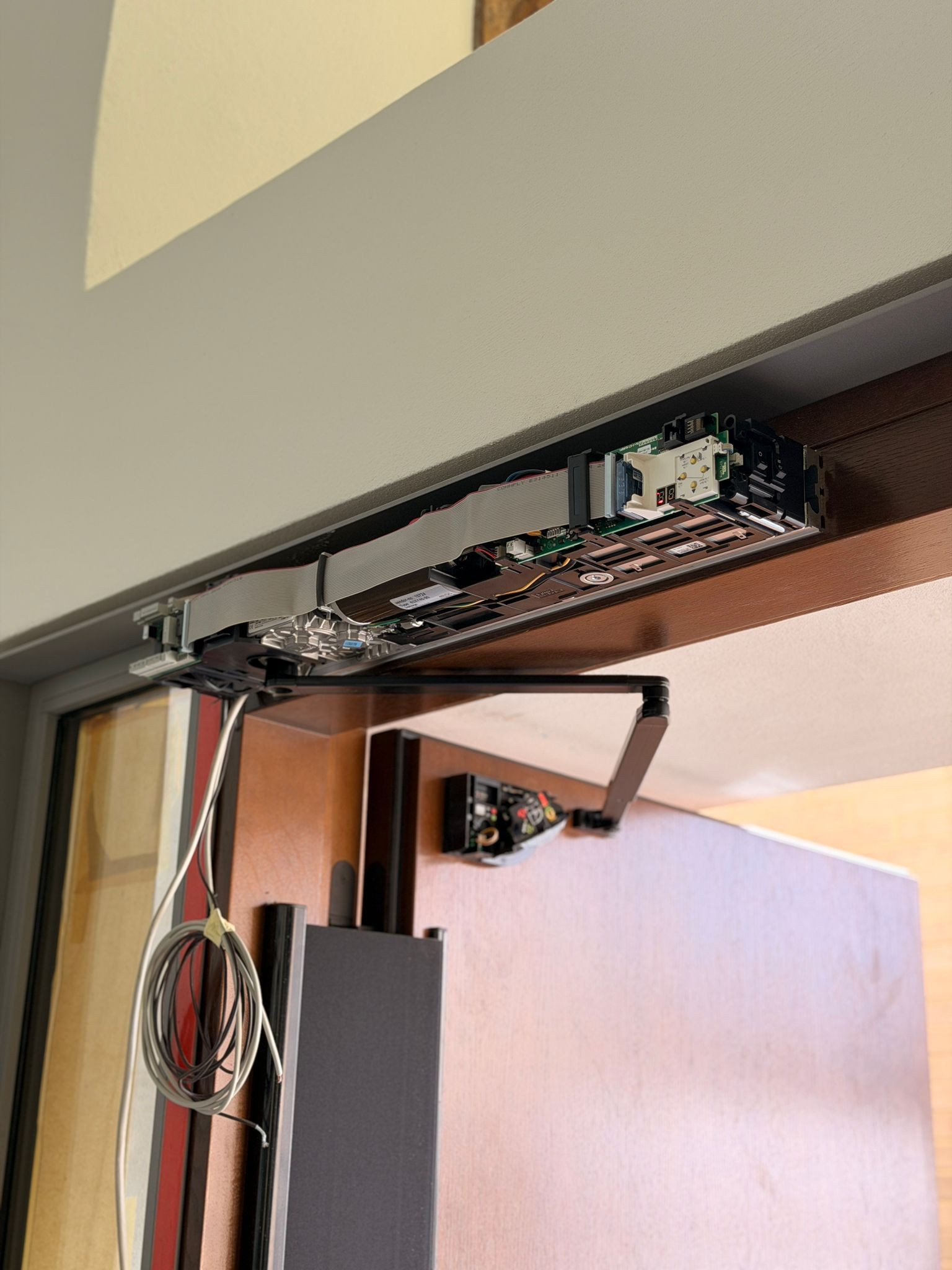 Automatische Schiebetüranlage mit geöffnetem Antriebsgehäuse während der Installation in einem öffentlichen Gebäude.