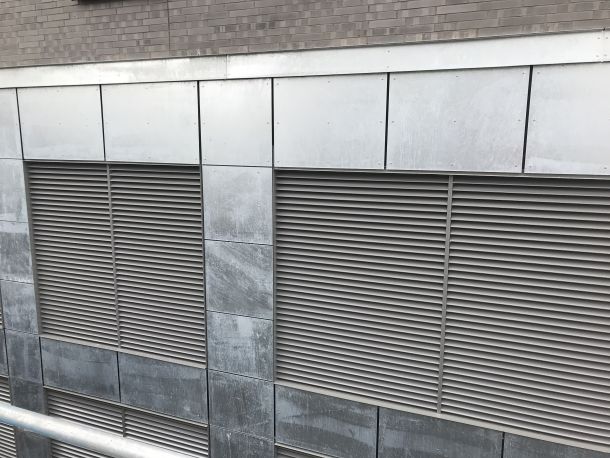 Einliegende Aluminium-Lüftungsgitter in einer Natursteinfassade für die kontrollierte Zu- und Abluftführung.