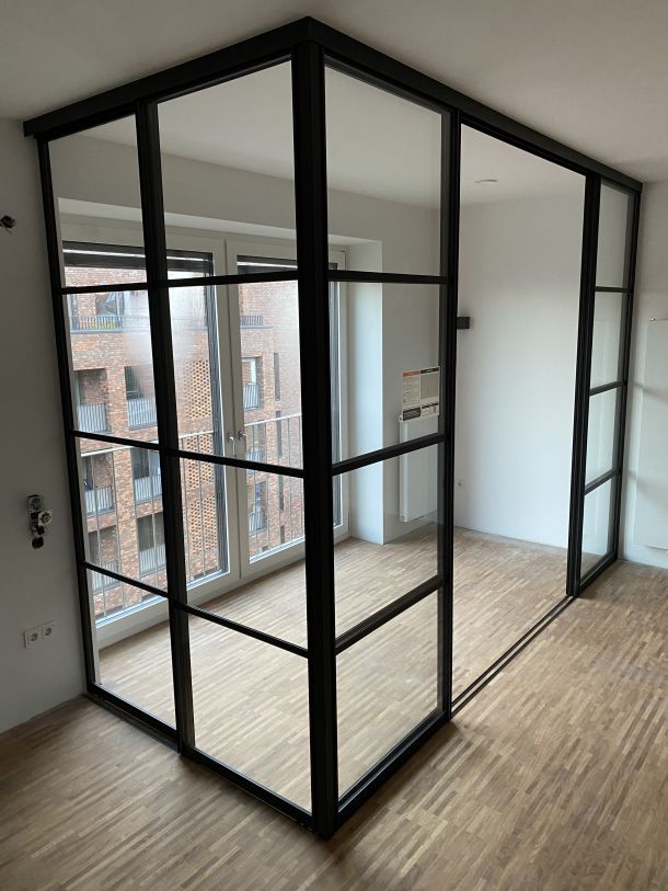 Eckverglaste Stahl-Glas-Konstruktion als stilvoller Raumteiler im modernen Loft-Design.