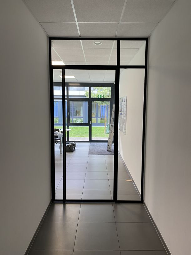 Glas-Trennwand mit Stahlrahmen zur lichtdurchlässigen Abtrennung von Fluren und Eingangsbereichen.